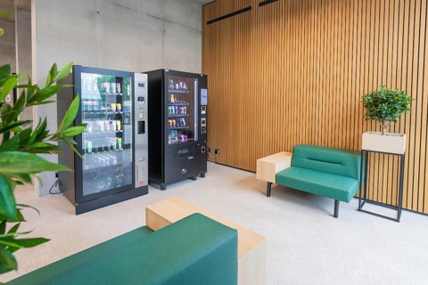 Modern seating area with vending machines, green plants and wooden walls, Boarding House des