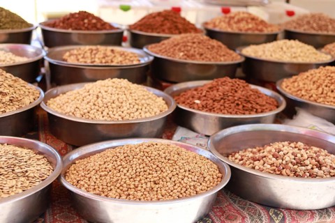 Various seeds and spices displayed in metal bowls at a market, showcasing an array of earthy