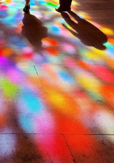 Shadows of two people and colorful spots of light on the floor through the stained glass windows by