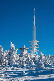 View over snow-covered spruce trees of the telecommunications tower and the radar station on the