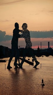 Person on stand-up paddle in front of Molecule Man, Molecule Men, sculpture, figures in the water