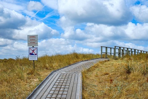 A wooden walkway leads across a dune to the beach in Vejbystrand, Skåne, Sweden. A wooden