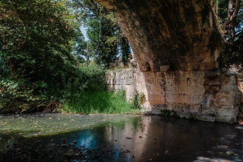 Roman Bridge across the river in Vrises, Crete, Greece, A stone bridge over a calm river surrounded