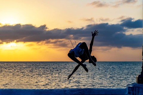 Acrobatic jump into the sea at sunset in Sao Luis, Maranhao, Sao Luis, Maranhao, Brazil