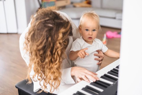 Mother and child play piano together with focused interaction in a home environment