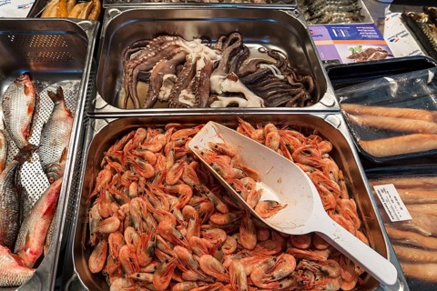 Prawns (Brachyura), with a squid (Coleoidea) in the background, at a weekly market market in
