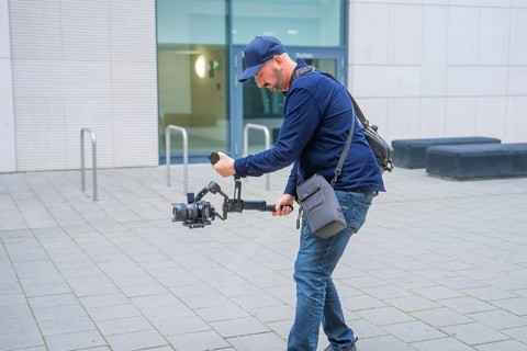 Man with gimbal and camera running outside a modern building, Milaneo, Stuttgart, Germany