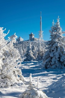 View of deep snow-covered coniferous forest to the Brocken summit under clear blue sky on a sunny