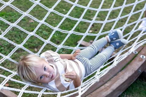 A young child enjoys a moment of relaxation in a hammock in backyard. Surrounded by nature, the
