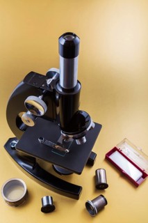 Vintage black Bausch & Lomb research microscope with box of glass slides and objectives on light
