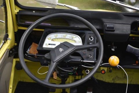 Interior of a vintage car with yellow dashboard and retro steering wheel, Citroën 2CV on a trailer,