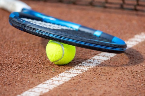 Tennis icon: close-up of a tennis ball and tennis racket on a clay court