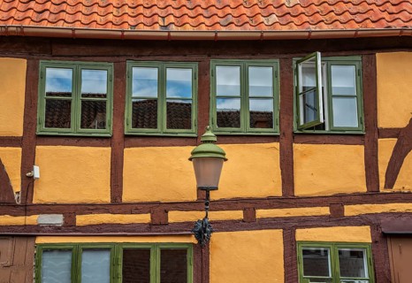 Part of the facade with windows and street lamp of an older half-timbered house in Ystad, Skåne