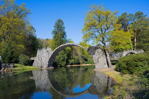 Majestic stone bridge and its reflection surrounded by green forest, Rakotz Bridge, Devil's Bridge,
