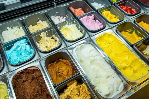 Scoops of colorful gelato and sorbet lined in a display case, showcasing a vibrant assortment of