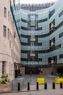 The curved glass extension of BBC Broadcasting House rises beside its original Portland stone