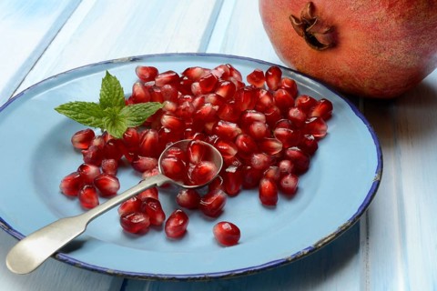 Pomegranate seeds and spoons on plate, Punica granatum