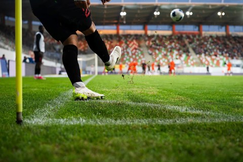 Close-up of soccer player kicking a football on a professional grass field, capturing dynamic