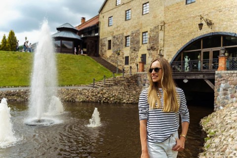 Smiling long-haired woman in a striped jumper near the fountain in summer, A woman in sunglasses