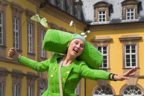An artistic performance by a fairytale-like costumed stilt walker, visually impressive walking act,