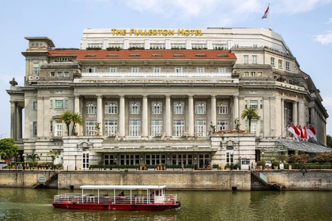 Tourist boat cruises on the river past the colonnaded facade of the former General Post Office