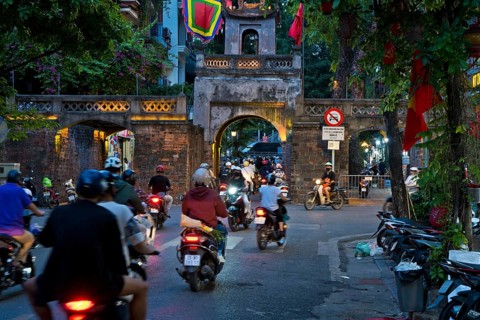 City gate during the evening rush hour on a busy street with mopeds, scooters, motorbikes and