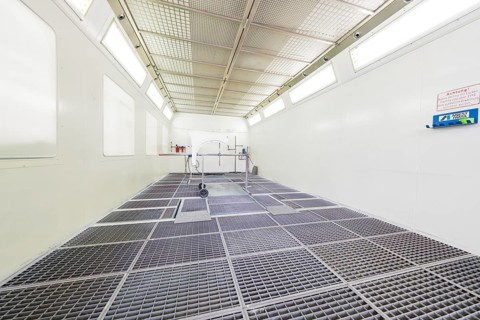 Empty painting booth with bright light and mesh floor, sterile industrial environment, painter,