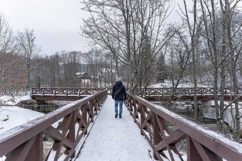 Rear view of a man walking on a wooden bridge in winter, A person walks on a snow-covered bridge in