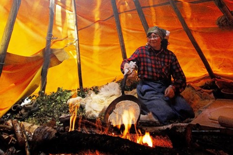 Baking bread the traditional Sami way in a pan over an open fire in a tent poop, Lapland, Sweden