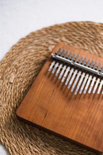 A wooden kalimba with metal tines placed on a woven mat, evoking a rustic feel