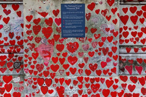Hundreds of hand painted red and pink hearts crowd a section of the National Covid Memorial Wall,