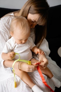 A mother and child engage playfully with colorful ribbons, fostering a close bond and joyful