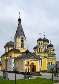 Orthodox church with yellow façade and black domes under cloudy sky, Hîncu monastery, Hâncu,