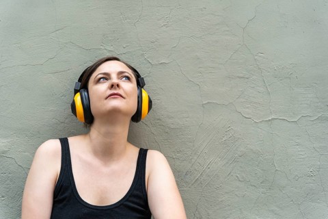 Blonde woman 40s in yellow headphones lost in music, close-up urban portrait, A woman with