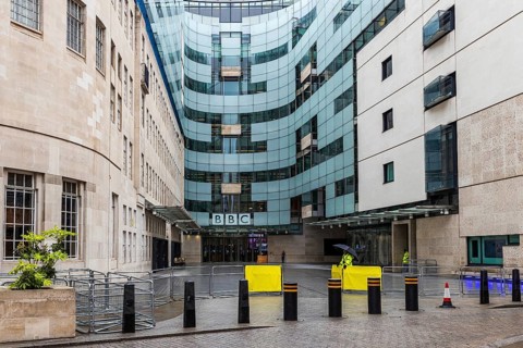 Contrasting glass and Portland stone wings meet at the entrance of BBC Broadcasting House, London,