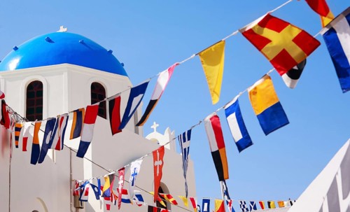 Classic Greek blue dome church and flags in Oia on Santorini, Greece, Santorini island, Aegean Sea,