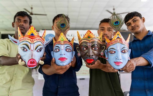 Students display traditional masks they created, in a traditional mask-making workshop during an