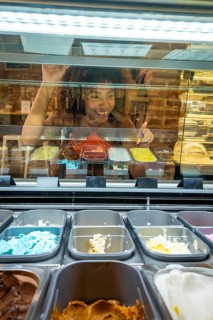 Smiling young woman looking at a transparent display counter filled with delicious, brightly