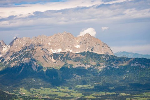 Massive mountain range under dramatic cloud formations and dense forest, Hahnenkamm, Kitzbühel,