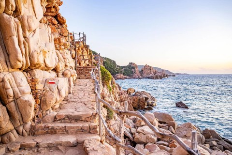 A little trail passing the rocks at the coastline with blue water at Costa Paradiso on a sunny day