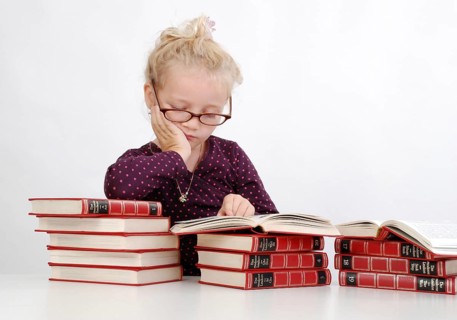 Old wise little girl with encyclopedias is learning