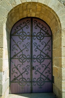 Ornate purple door set in a stone archway. porch of romanesque church of Saint-Saturnin. Puy de