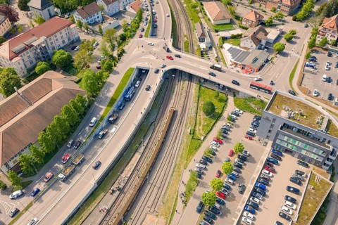 Urban aerial view with rails, intersection and surrounding buildings, construction site by Leonhard