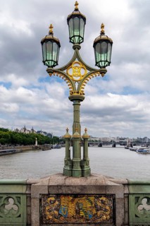 A three headed cast iron lamp post stands on Westminster Bridge above a heraldic panel, part of the