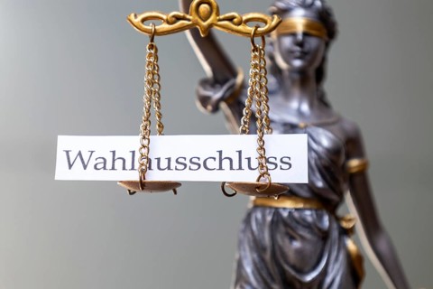 On the scales of Justice lies a sign bearing the words ‘EXCLUSION FROM ELECTION' (illustrative