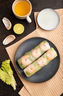 Vietnamese shrimp spring rolls on black concrete background and beige linen textile. top view, flat