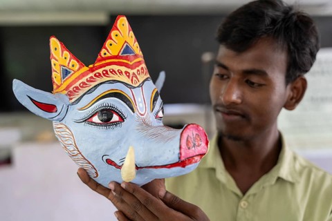 A student holds a traditional mask he created, in a traditional mask-making workshop during an