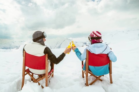 Couple relax sit on chairs in snowy ski resort with beer bottle, concept of leisure, winter