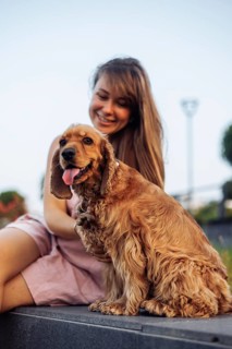 An intimate outdoor moment between a woman and her happy dog in the sun