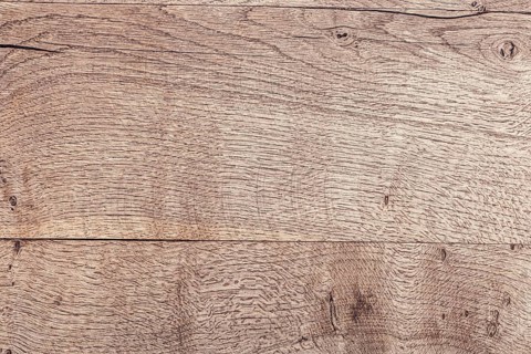 Close-up of a textured wooden surface with natural grain patterns. The wood is light brown with